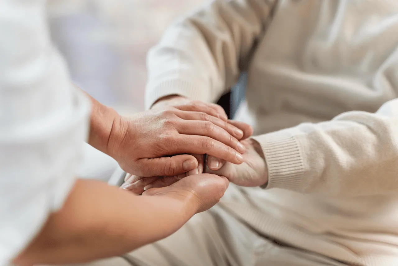 Pflegekraft hält die Hand eines Seniors — ambulante Grundpflege in Bochum